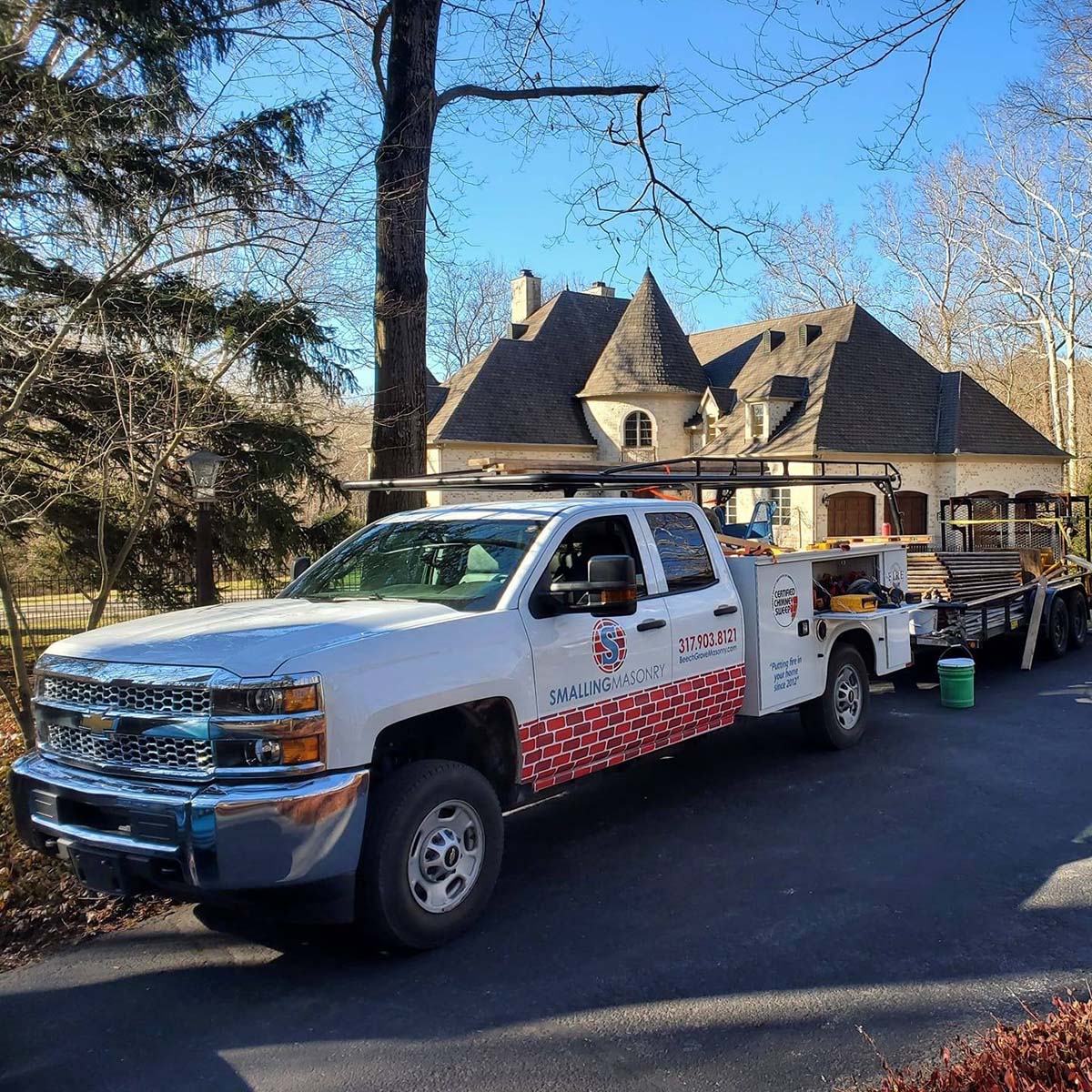 The Smalling Masonry work truck wrapped with a brick design and the Smalling Masonry logo. There is a tudor house in the background.