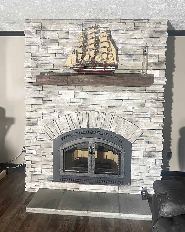 Grey stone fireplace with a wood mantelpiece