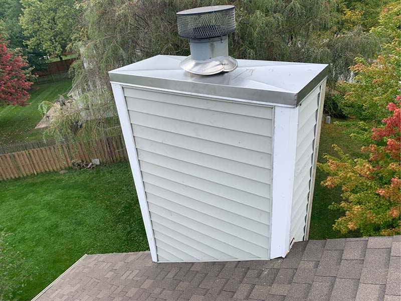 A brand new silver chase cover and trim on a white chimney