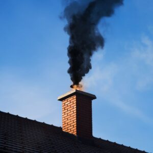 a masonry chimney with some flames and thick black smoke coming out of the top