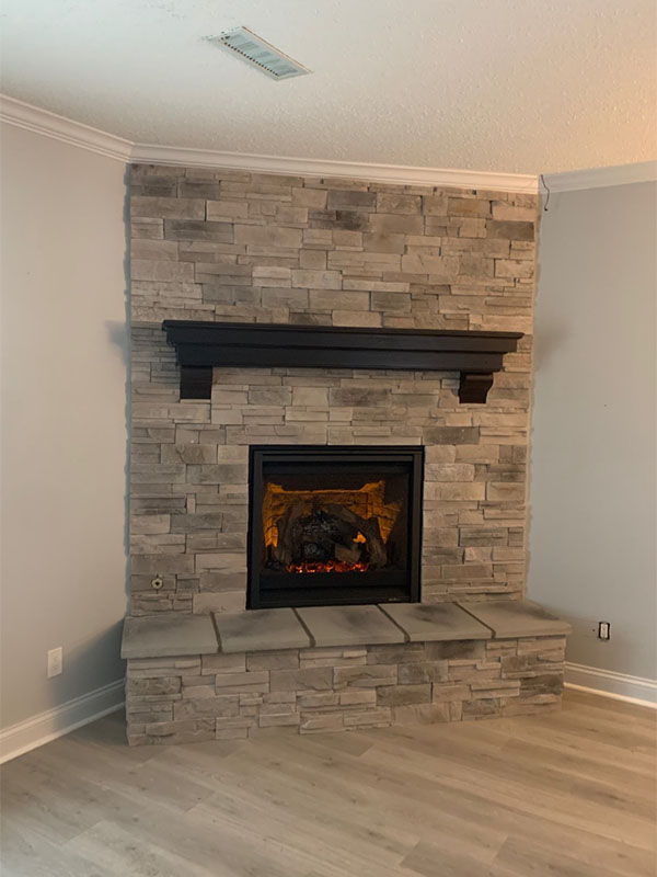 Light gray stone fireplace with a dark mantelpiece