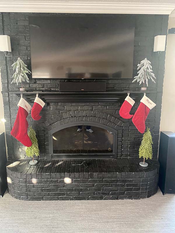 A black painted brick fireplace before remodel with Christmas decorations