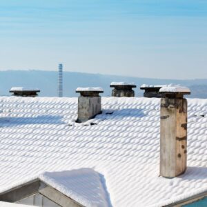 a view of snow-covered rooftops, all of which have at least one chimney