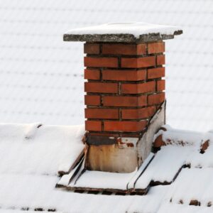 a masonry chimney with snow on the top surrounded by a snowy roof